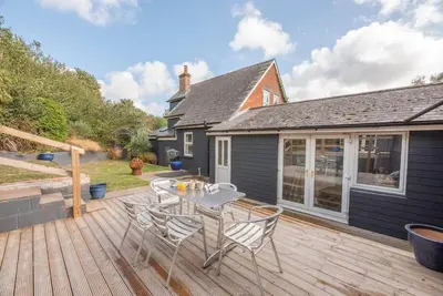a patio with a table and chairs on a deck at The Red House, Leiston in Woodbridge
