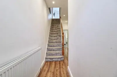 a staircase in a home with white walls and wooden floors at Ivy on Sea Villa in Southend-on-Sea