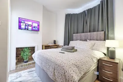 a bedroom with a bed and a fireplace at Ivy on Sea Villa in Southend-on-Sea