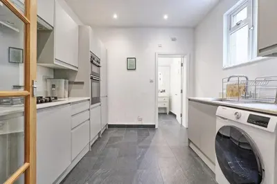 a kitchen with white cabinets and a washer at Ivy on Sea Villa in Southend-on-Sea