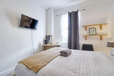a bedroom with a bed and a tv on a wall at Ivy on Sea Villa in Southend-on-Sea