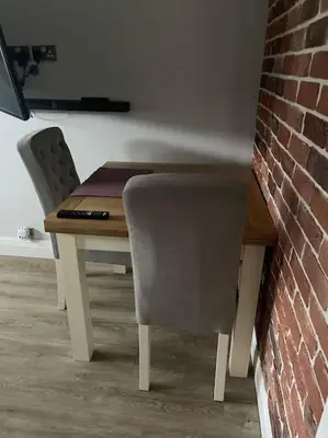 a dining room table with two chairs and a brick wall at Modern Luxe Maisonette Near Station With Free Parking in Billericay