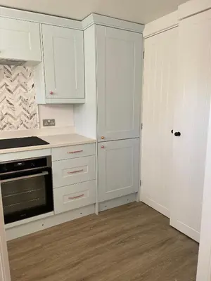a white kitchen with white cabinets and a door at Modern Luxe Maisonette Near Station With Free Parking in Billericay