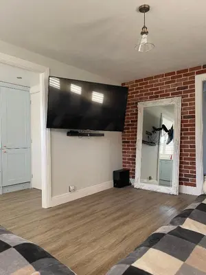 a living room with a large flat screen tv on a brick wall at Modern Luxe Maisonette Near Station With Free Parking in Billericay