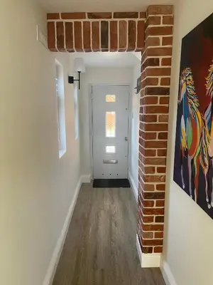 an empty hallway with a brick wall and a door at Modern Luxe Maisonette Near Station With Free Parking in Billericay
