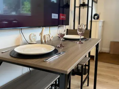 a wooden table with two plates and wine glasses at Bibis Home - Hertford in Hertford