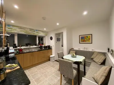 a living room with a table and a kitchen at Tresco - Aldeburgh's hidden gem in Aldeburgh