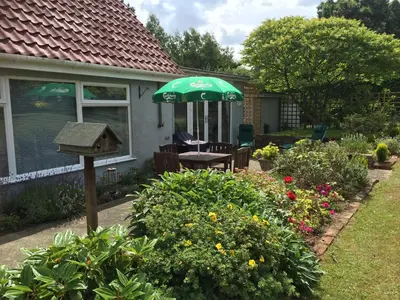 a house with a green umbrella and a bird house at Tresco - Aldeburgh's hidden gem in Aldeburgh