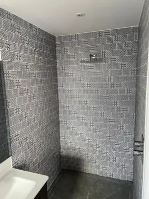 a bathroom with a gray tiled shower with a sink at The Snug at Fourleys in Woodhurst