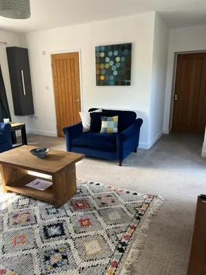 a living room with a blue couch and a coffee table at The Snug at Fourleys in Woodhurst