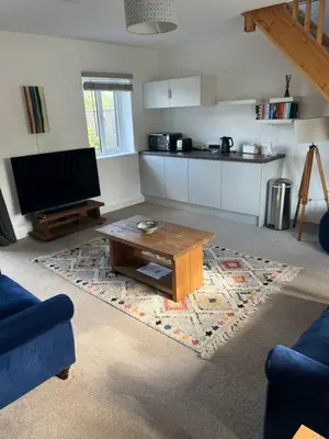 a living room with a coffee table and a kitchen at The Snug at Fourleys in Woodhurst