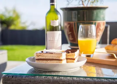 a piece of cake on a plate next to a bottle of wine at 4x Bed Luxurious Home With a View in Downham Market