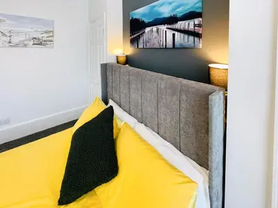 a bedroom with a bed with yellow pillows at Sea Leigh in Leigh-on-Sea