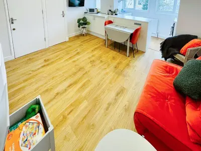 a living room with a red couch and a wooden floor at Sea Leigh in Leigh-on-Sea