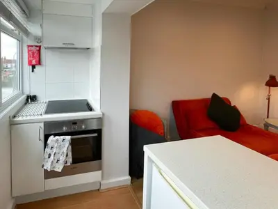 a small kitchen with a stove and a red couch at Sea Leigh in Leigh-on-Sea