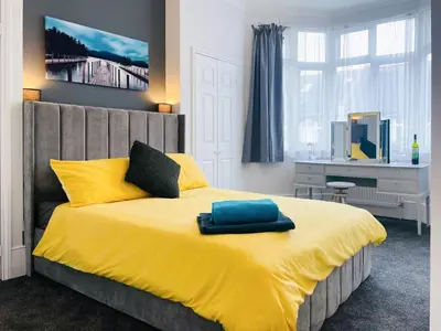 a bedroom with a large bed with a yellow blanket at Sea Leigh in Leigh-on-Sea