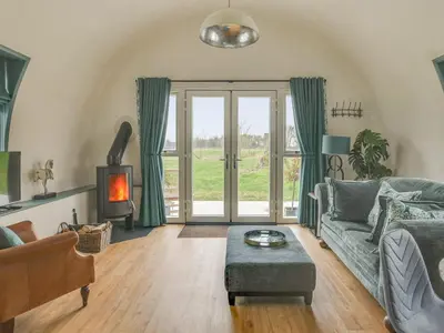 a living room with a couch and a fireplace at The Nissen Hut in Laxfield