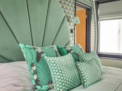 a bed with a green headboard and pillows on it at The Nissen Hut in Laxfield