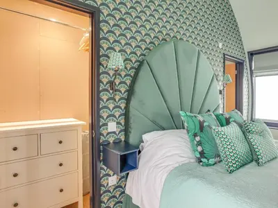 a bedroom with a bed with a green headboard at The Nissen Hut in Laxfield