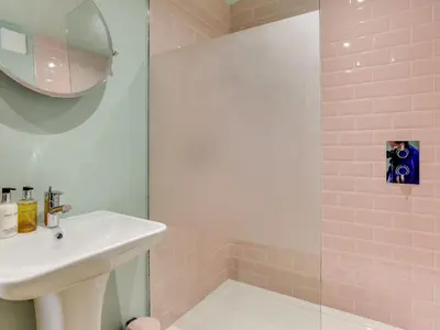 a pink bathroom with a sink and a mirror at The Nissen Hut in Laxfield
