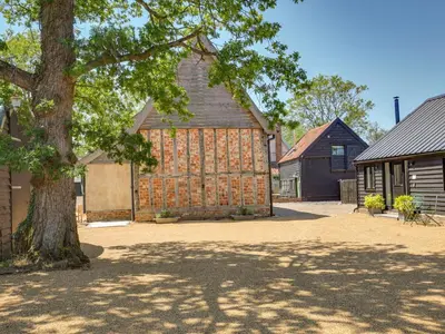 a large barn with a tree in front of it at The Nissen Hut in Laxfield