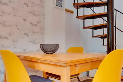 a dining room with a wooden table and yellow chairs at 25A City Road · Luxury City centre townhouse with courtyard Pass the Keys in Cambridge