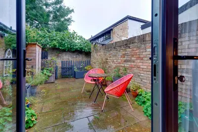 a patio with two red chairs and a table at 25A City Road · Luxury City centre townhouse with courtyard Pass the Keys in Cambridge