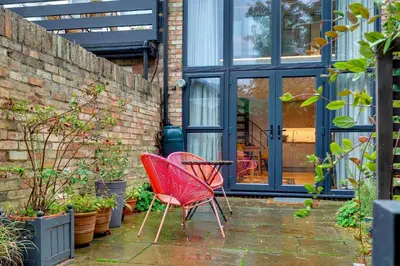 two red chairs sitting on a patio with plants at 25A City Road · Luxury City centre townhouse with courtyard Pass the Keys in Cambridge