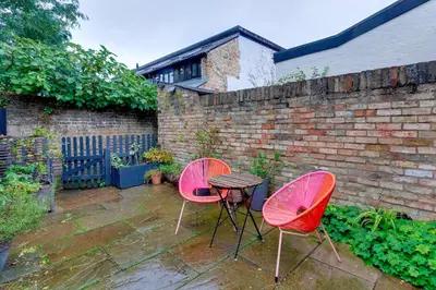 two pink chairs and a table in a garden at 25A City Road · Luxury City centre townhouse with courtyard Pass the Keys in Cambridge