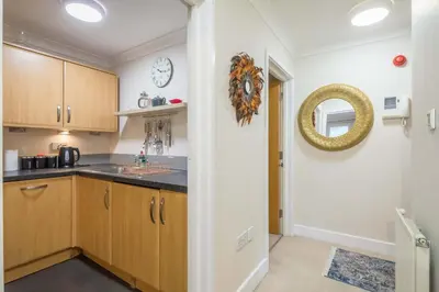 a kitchen with wooden cabinets and a clock on the wall at Fabulous Central 3Bed Apt - With Parking in Cambridge