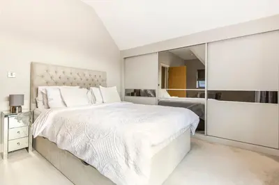 a white bedroom with a large bed and a mirror at Contemporary 3 Bedroom Fully Detached Town House in Wickford