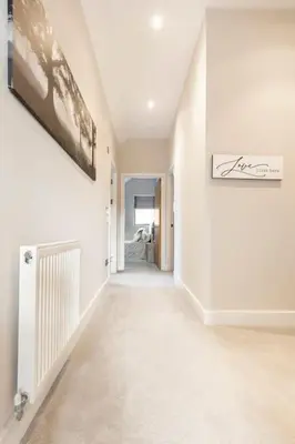 a hallway with white walls and a painting on the wall at Contemporary 3 Bedroom Fully Detached Town House in Wickford