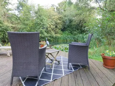 three wicker chairs and a table on a deck at Brook Lodge in Ipswich