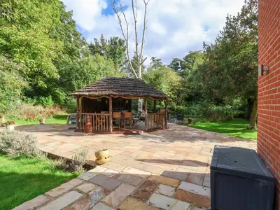 a wooden gazebo on a patio in a yard at Brook Lodge in Ipswich