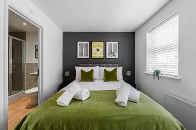 a bedroom with a large bed with green blanket at Caboose Stays - Bury St Edmunds - Modern 4 Bed townhouse close to centre and major transport links - Fast Wifi - Parking - Business and Contractors in Bury Saint Edmunds