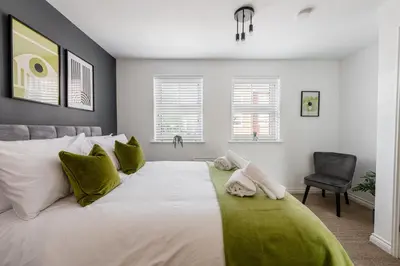 a bedroom with a large white bed with green pillows at Caboose Stays - Bury St Edmunds - Modern 4 Bed townhouse close to centre and major transport links - Fast Wifi - Parking - Business and Contractors in Bury Saint Edmunds