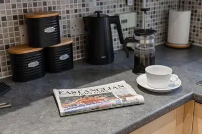 a magazine sitting on a counter with a coffee maker and a cup at Caboose Stays - Bury St Edmunds - Modern 4 Bed townhouse close to centre and major transport links - Fast Wifi - Parking - Business and Contractors in Bury Saint Edmunds