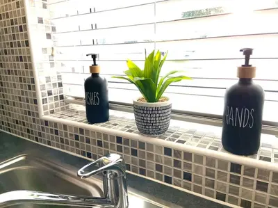 three bottles sitting on a window sill next to a sink at Caboose Stays - Bury St Edmunds - Modern 4 Bed townhouse close to centre and major transport links - Fast Wifi - Parking - Business and Contractors in Bury Saint Edmunds