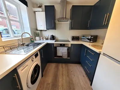 a kitchen with blue cabinets and a sink and a dishwasher at Hythe House - Stylish Stay for Families & Groups by Catchpole Stays in Colchester