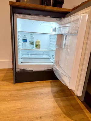 an open refrigerator with bottles of water in it at Bespoke 1 Bedroom Barn by Stansted Airport & Holiday Parking in London Stansted Airport