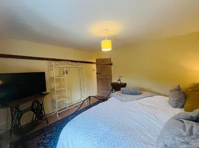 a bedroom with a large bed and a flat screen tv at Beautifully Quaint Cottage in Yelling