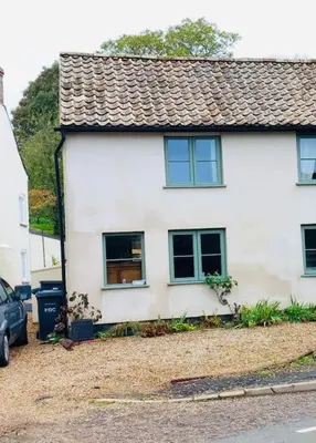 a white house with a car parked in front of it at Beautifully Quaint Cottage in Yelling