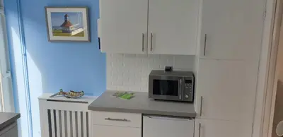 a kitchen with white cabinets and a microwave on a counter at Rainbow on Sea Frinton-on-Sea in Kirby Cross