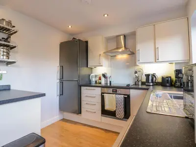 a kitchen with white cabinets and a stainless steel refrigerator at 25 Resbury Close in Cambridge