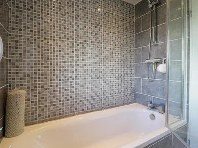 a bathroom with a tub and a tiled wall at 25 Resbury Close in Cambridge
