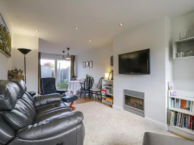 a living room with a leather couch and a fireplace at 25 Resbury Close in Cambridge