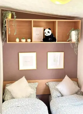a bedroom with two beds and a panda bear on shelves at Beatrice homes in Parkeston