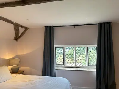 a bedroom with a bed and a large window at Potton Hall in Saxmundham