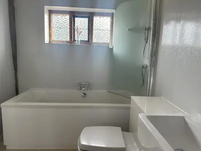 a white bathroom with a tub and a toilet at Potton Hall in Saxmundham