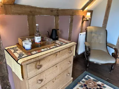 a wooden dresser with a bottle of whiskey and a chair at Potton Hall in Saxmundham